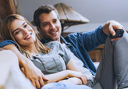 Smiling young couple relaxing and watching TV at home